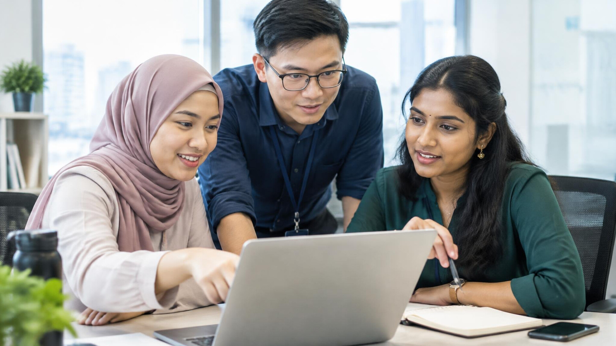 Team of Malaysian professionals discussing software on a laptop